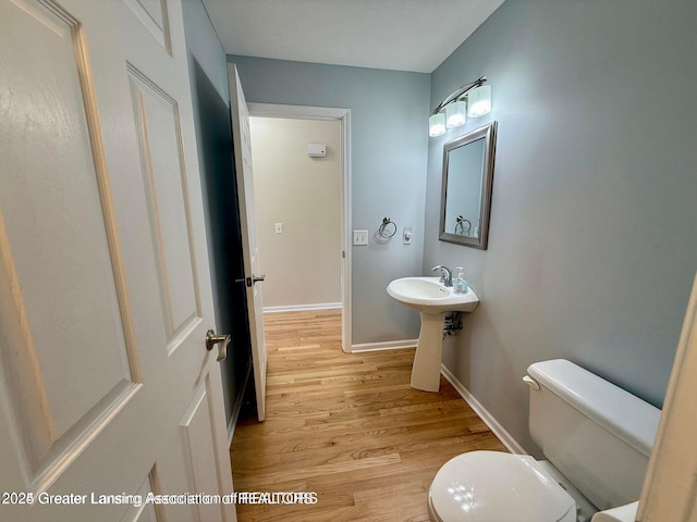 bathroom featuring baseboards, toilet, and wood finished floors