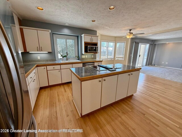 kitchen with tile countertops, light wood-style flooring, a sink, white cabinets, and appliances with stainless steel finishes