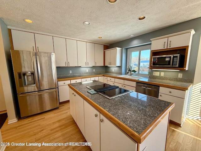 kitchen with light wood-style flooring, a sink, stainless steel appliances, tile counters, and white cabinets