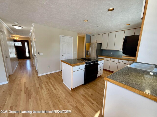 kitchen with black appliances, white cabinets, light wood-style floors, a textured ceiling, and a center island