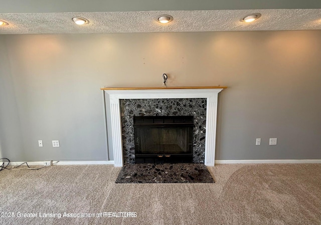 room details featuring a premium fireplace, baseboards, carpet, and a textured ceiling