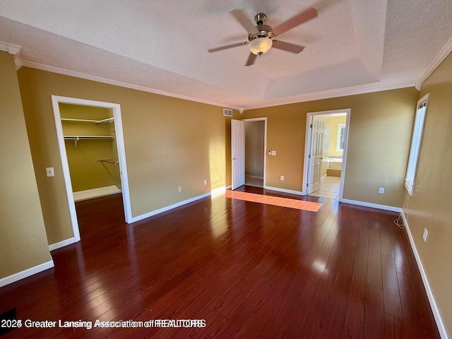 unfurnished bedroom featuring visible vents, hardwood / wood-style flooring, a textured ceiling, crown molding, and baseboards