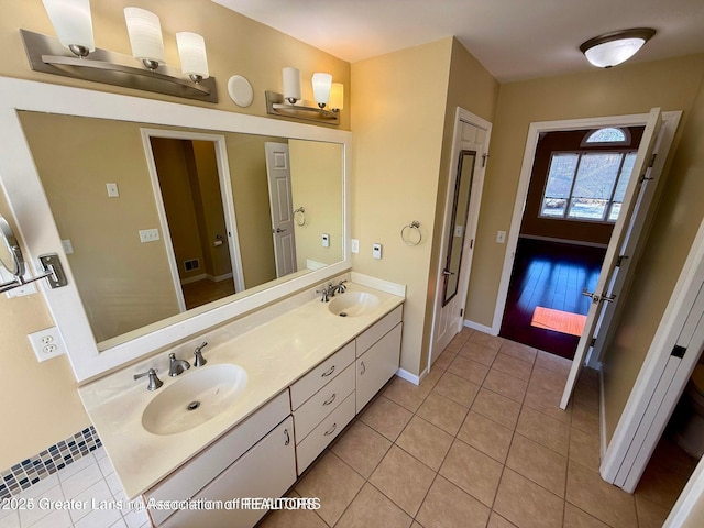 bathroom featuring tile patterned flooring, double vanity, baseboards, and a sink