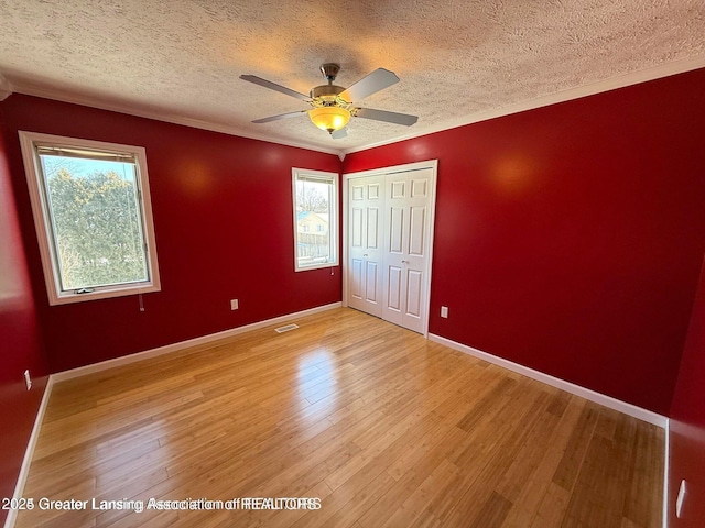 unfurnished bedroom featuring light wood-type flooring, baseboards, and visible vents