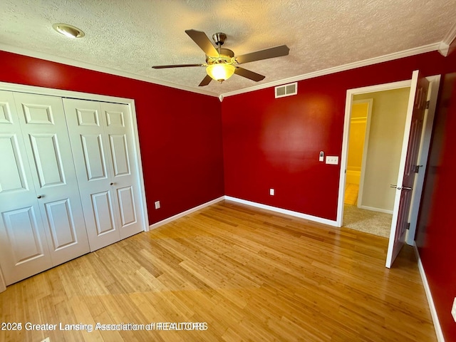 unfurnished bedroom featuring visible vents, crown molding, a textured ceiling, and light wood-type flooring