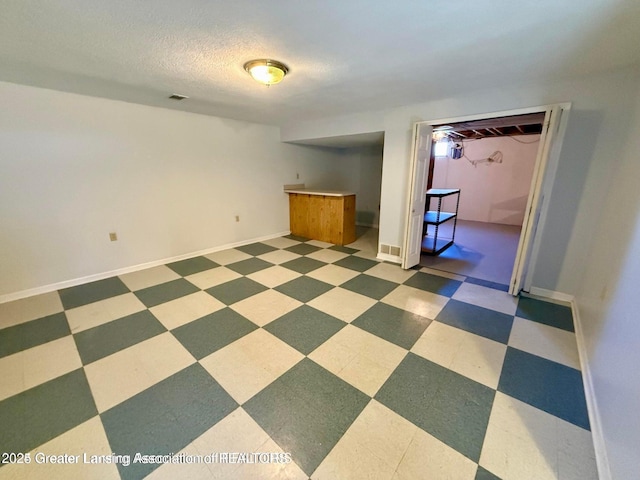 empty room with tile patterned floors, baseboards, visible vents, and a textured ceiling