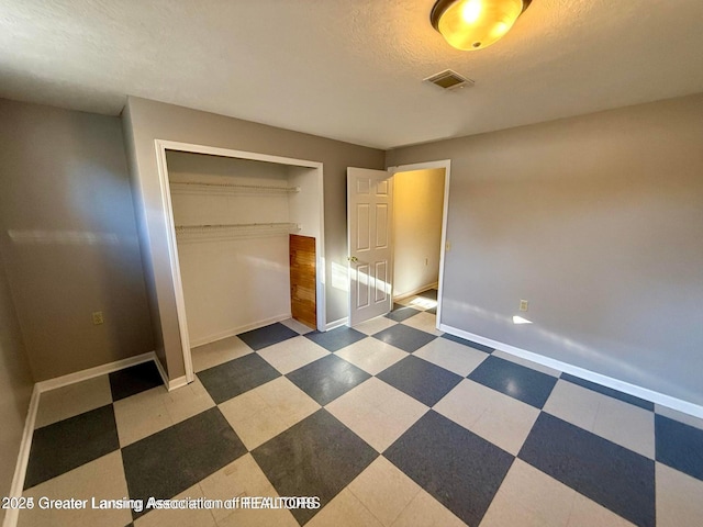 unfurnished bedroom with tile patterned floors, visible vents, baseboards, and a closet