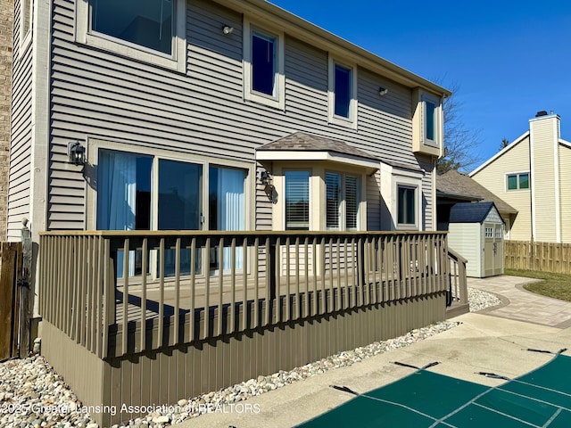 back of house with a patio, an outbuilding, a deck, and fence