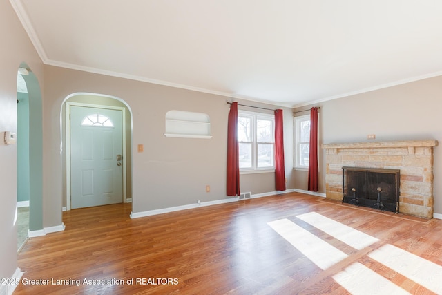 unfurnished living room featuring visible vents, baseboards, ornamental molding, light wood-style flooring, and a fireplace