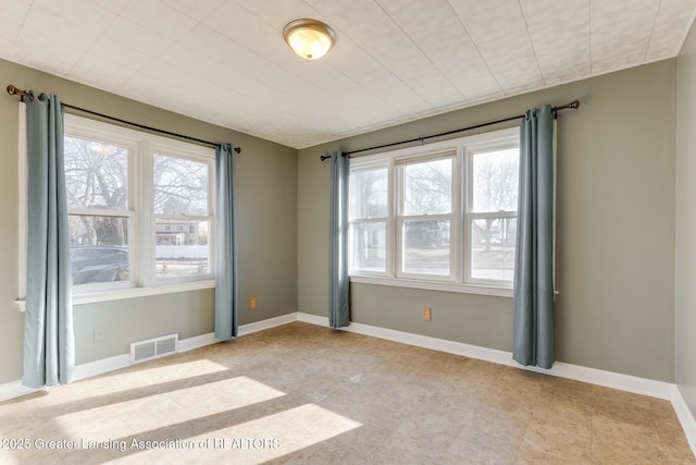 unfurnished room featuring baseboards, visible vents, and a wealth of natural light