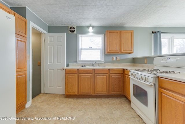 kitchen featuring a wealth of natural light, white appliances, light countertops, and a sink