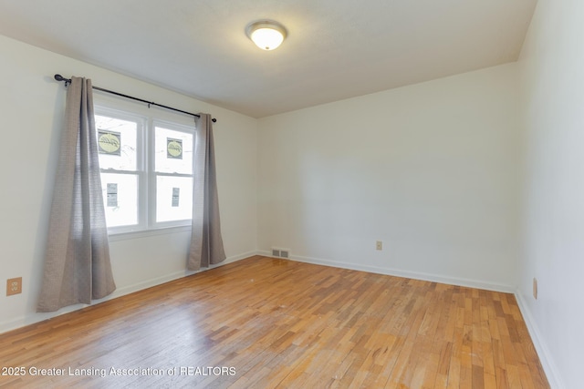 unfurnished room with visible vents, light wood-type flooring, and baseboards