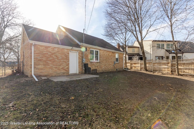 rear view of property with a patio area, fence, and brick siding