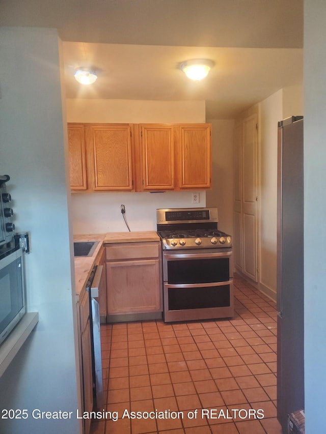 kitchen featuring light brown cabinetry, appliances with stainless steel finishes, and light countertops