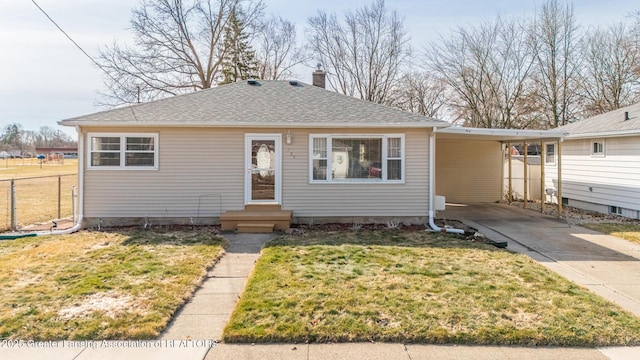 view of front facade featuring fence, concrete driveway, a front yard, an attached carport, and a chimney