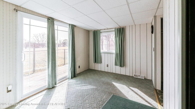 unfurnished room featuring visible vents, a paneled ceiling, and carpet floors