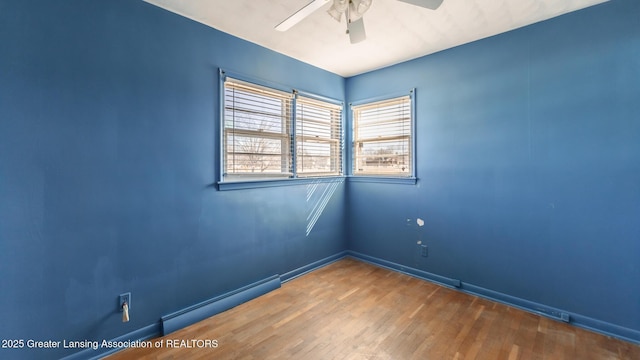 unfurnished room featuring baseboards, a baseboard heating unit, a ceiling fan, and wood finished floors