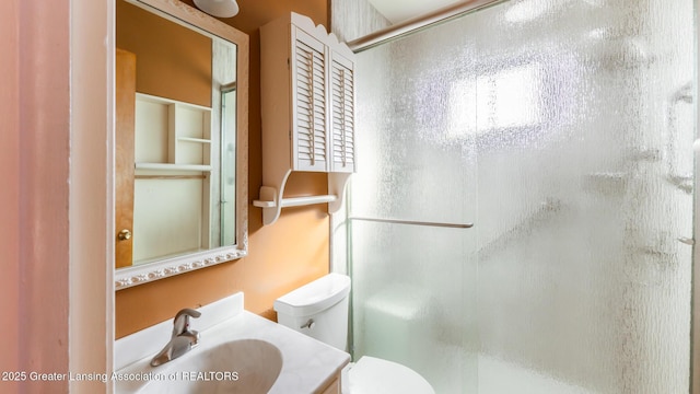 bathroom featuring a shower stall, toilet, and vanity