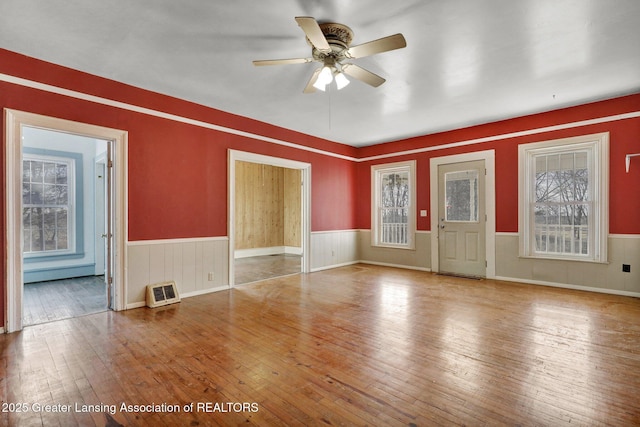 interior space with ceiling fan, wood-type flooring, and wainscoting