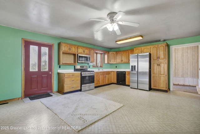 kitchen with a sink, stainless steel appliances, light countertops, light floors, and ceiling fan