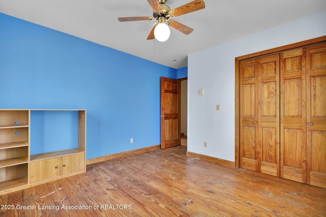 unfurnished bedroom featuring wood finished floors, baseboards, a closet, and ceiling fan