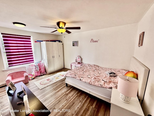 bedroom featuring ceiling fan, baseboards, and wood finished floors