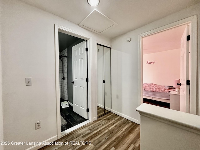 hallway with attic access, baseboards, and wood finished floors