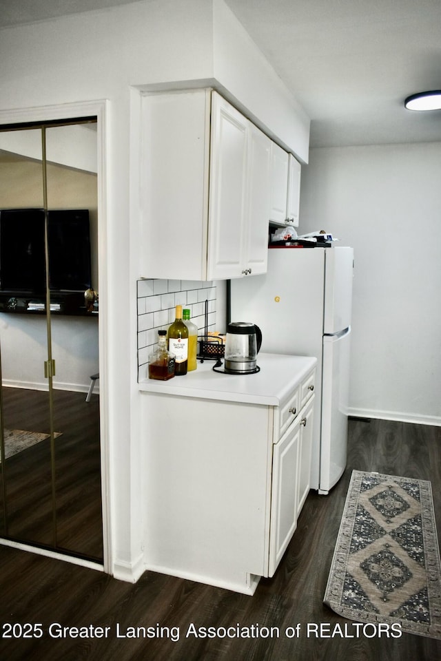 kitchen with dark wood finished floors, freestanding refrigerator, decorative backsplash, light countertops, and white cabinets