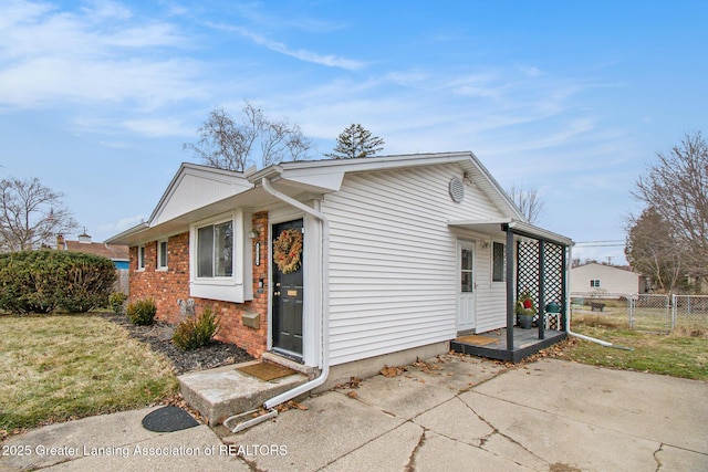 view of property exterior featuring a gate, a yard, brick siding, and fence