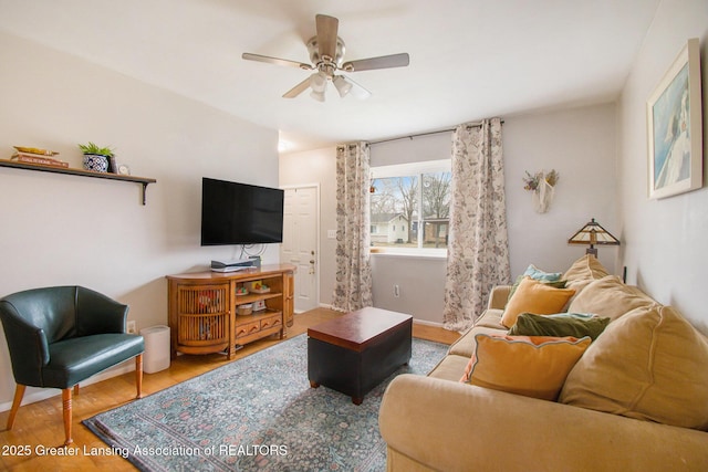 living room featuring ceiling fan, baseboards, and wood finished floors