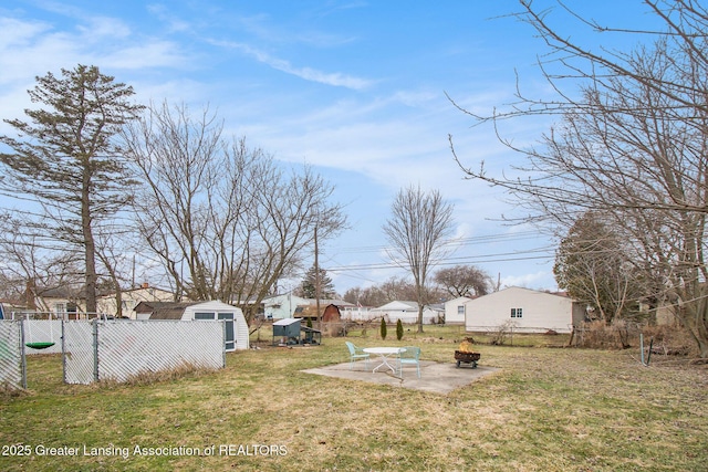 view of yard with a patio, fence, an outdoor structure, a fire pit, and a storage shed