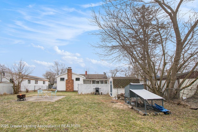 back of property featuring an outbuilding, a yard, a fenced backyard, a fire pit, and exterior structure