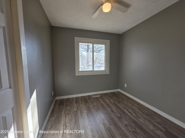 spare room with dark wood-type flooring, baseboards, visible vents, and a textured ceiling