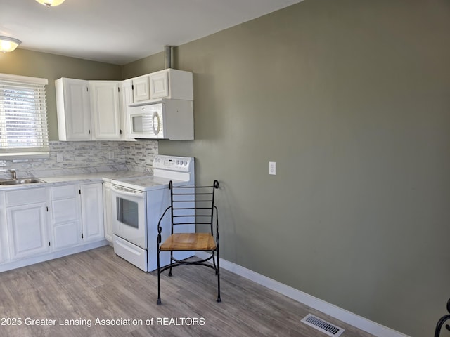 kitchen with white appliances, baseboards, visible vents, light wood finished floors, and decorative backsplash