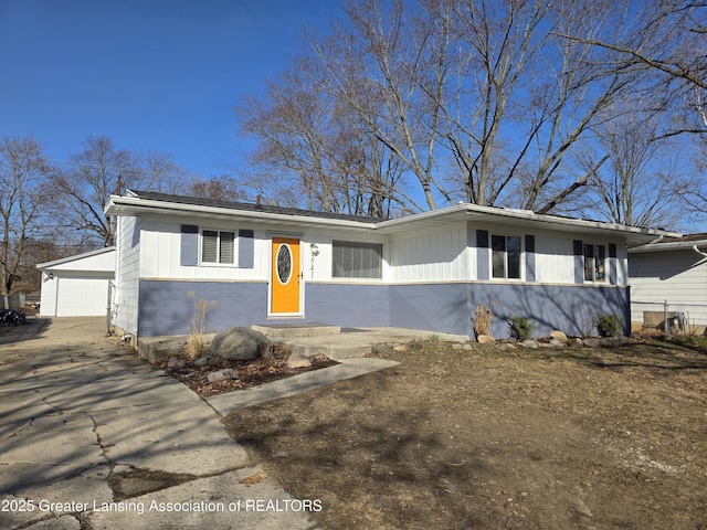 view of front of house featuring board and batten siding, a detached garage, brick siding, and an outdoor structure