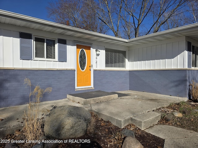 doorway to property featuring brick siding and board and batten siding