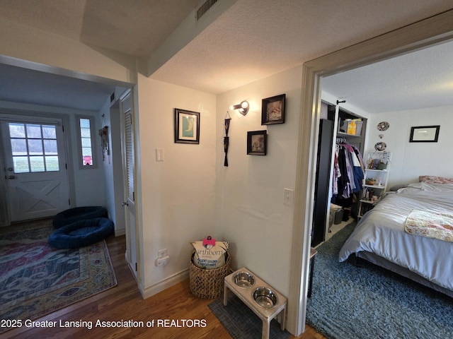 interior space featuring visible vents, a textured ceiling, baseboards, and wood finished floors