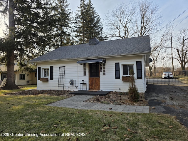 bungalow with aphalt driveway, a front lawn, and roof with shingles