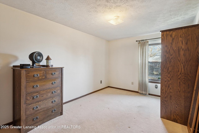 unfurnished bedroom with baseboards, light colored carpet, and a textured ceiling