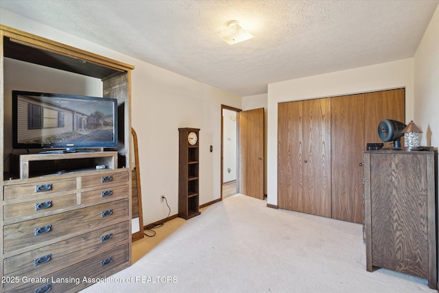 carpeted bedroom with a closet, baseboards, and a textured ceiling