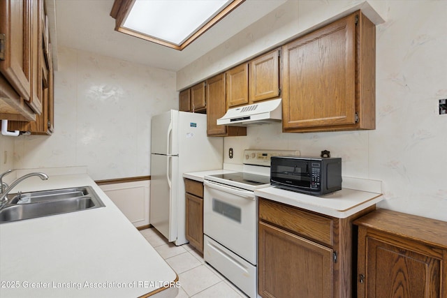 kitchen with under cabinet range hood, white appliances, light countertops, and a sink