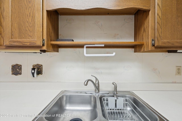 kitchen featuring brown cabinets, open shelves, light countertops, and a sink