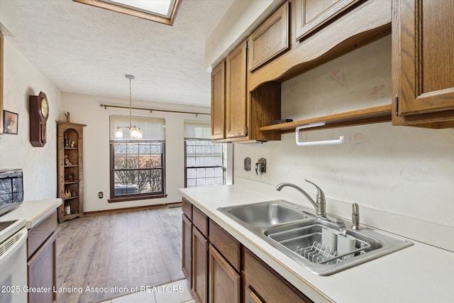 kitchen featuring a sink, open shelves, a textured ceiling, brown cabinetry, and light countertops