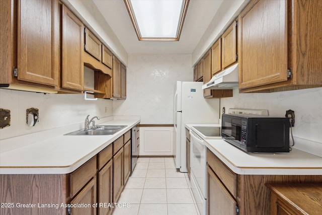 kitchen featuring electric range, under cabinet range hood, a sink, brown cabinetry, and black microwave