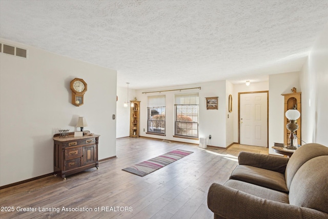 living area with hardwood / wood-style floors, baseboards, and visible vents