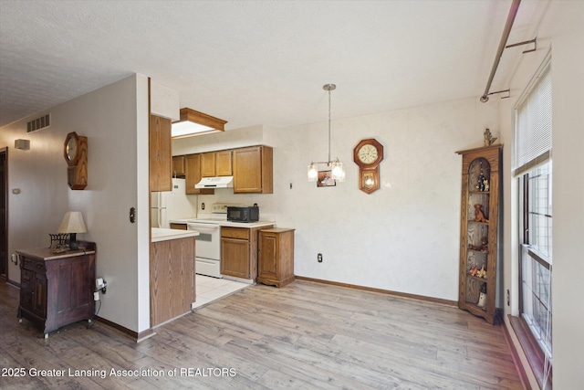 kitchen with visible vents, under cabinet range hood, light wood-style flooring, brown cabinetry, and white appliances