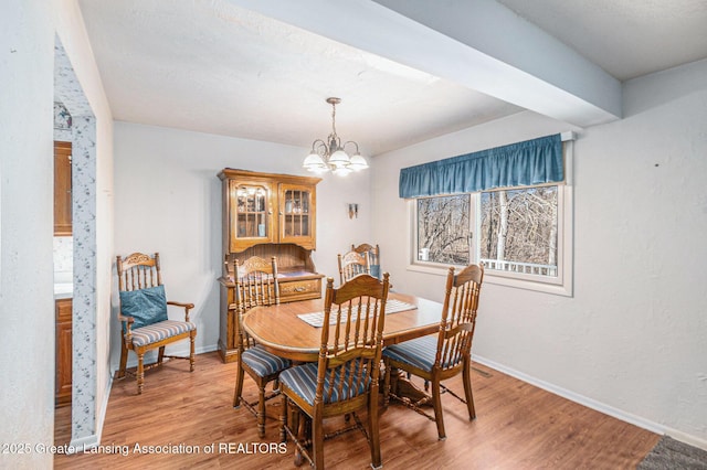 dining room featuring a chandelier, light wood-style flooring, and baseboards