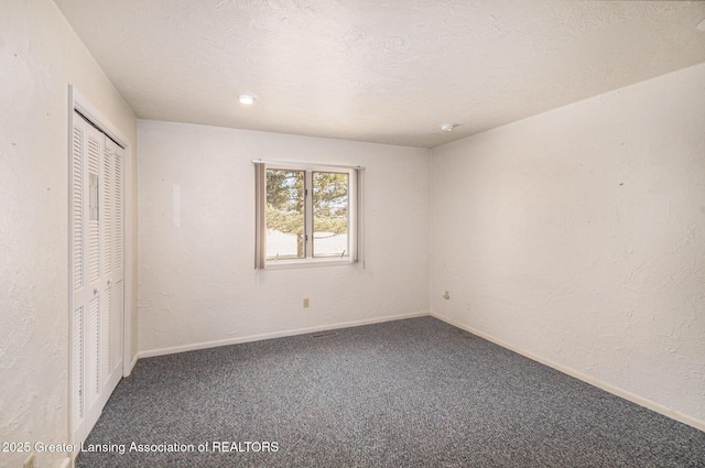 unfurnished bedroom with a textured wall, baseboards, carpet, and a textured ceiling