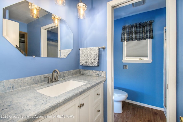 bathroom featuring visible vents, toilet, wood finished floors, baseboards, and vanity