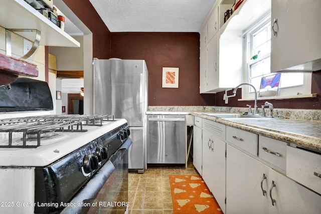 kitchen with a sink, stainless steel appliances, light countertops, white cabinets, and a textured ceiling